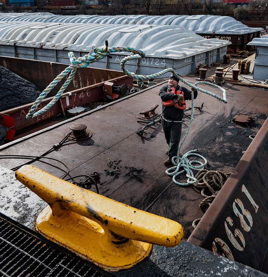 commercial photo of tug boat deckhand throwing a line to tie off boat.